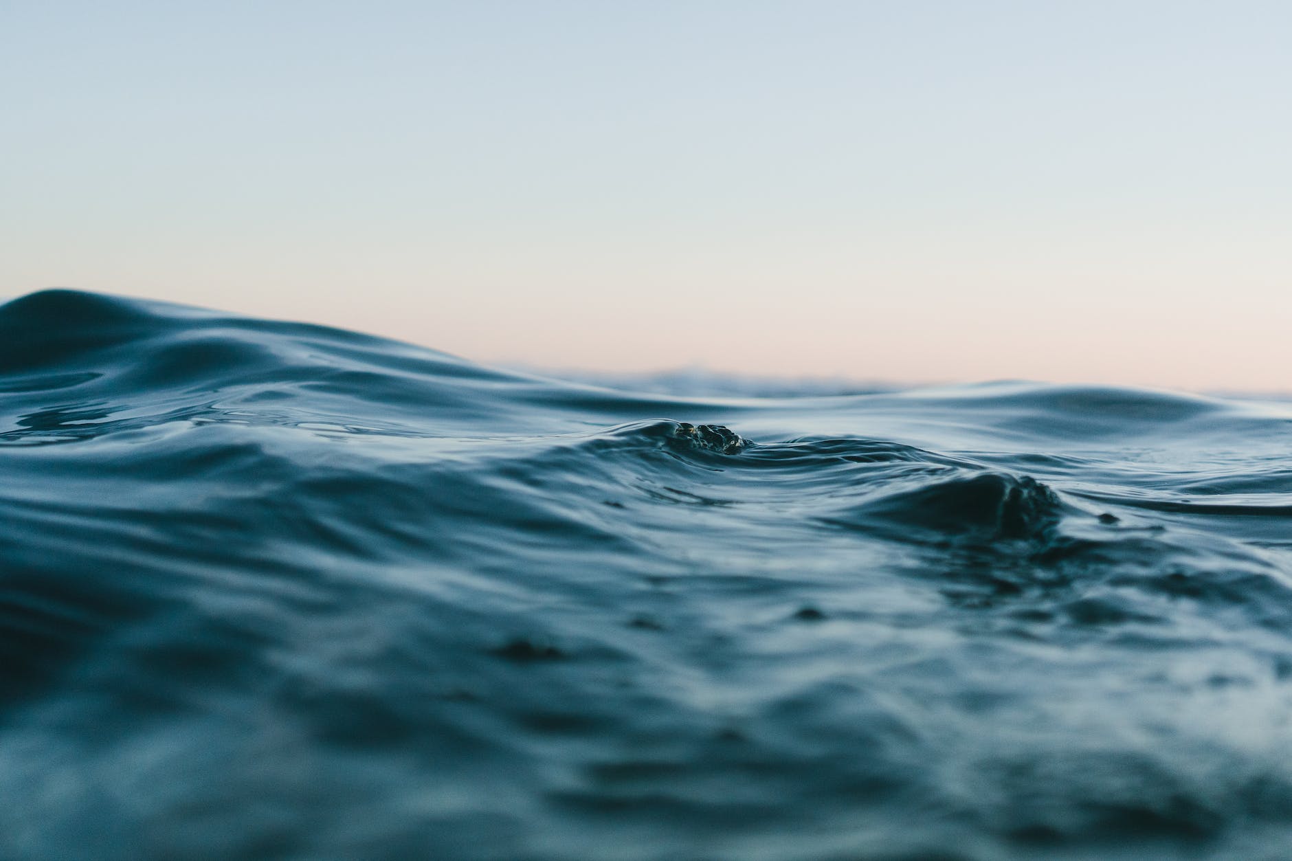 A close-up view of calm ocean waves with a soft gradient sky in the background.